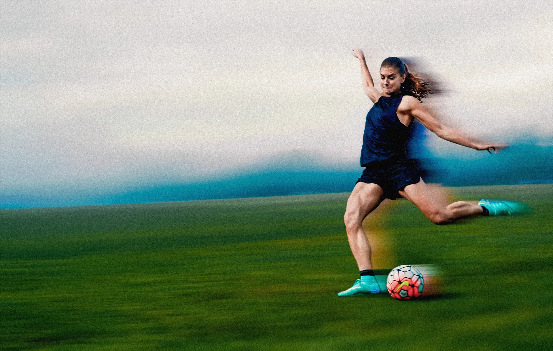 A footballer striking a ball across a studio field